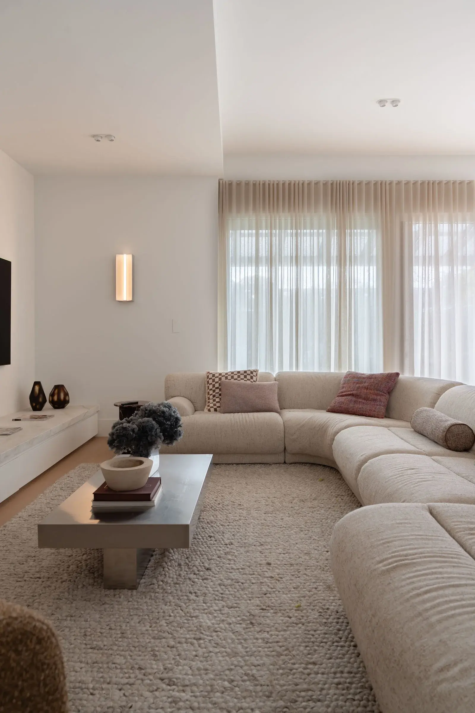 Cream modular sofa beneath sheer curtains in the family living room