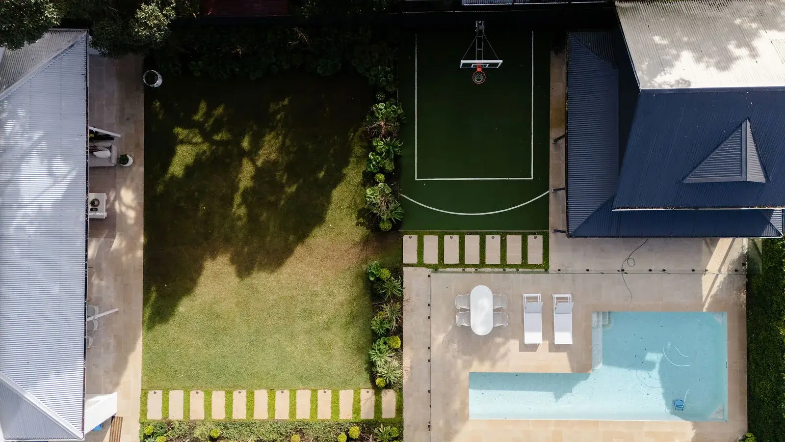 Aerial view over the rear garden, heated pool and mini basketball court