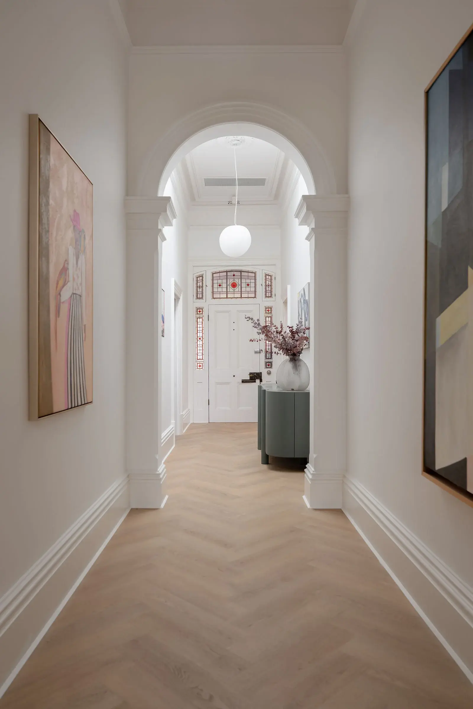 Arched entry hall with stained-glass door and herringbone floor