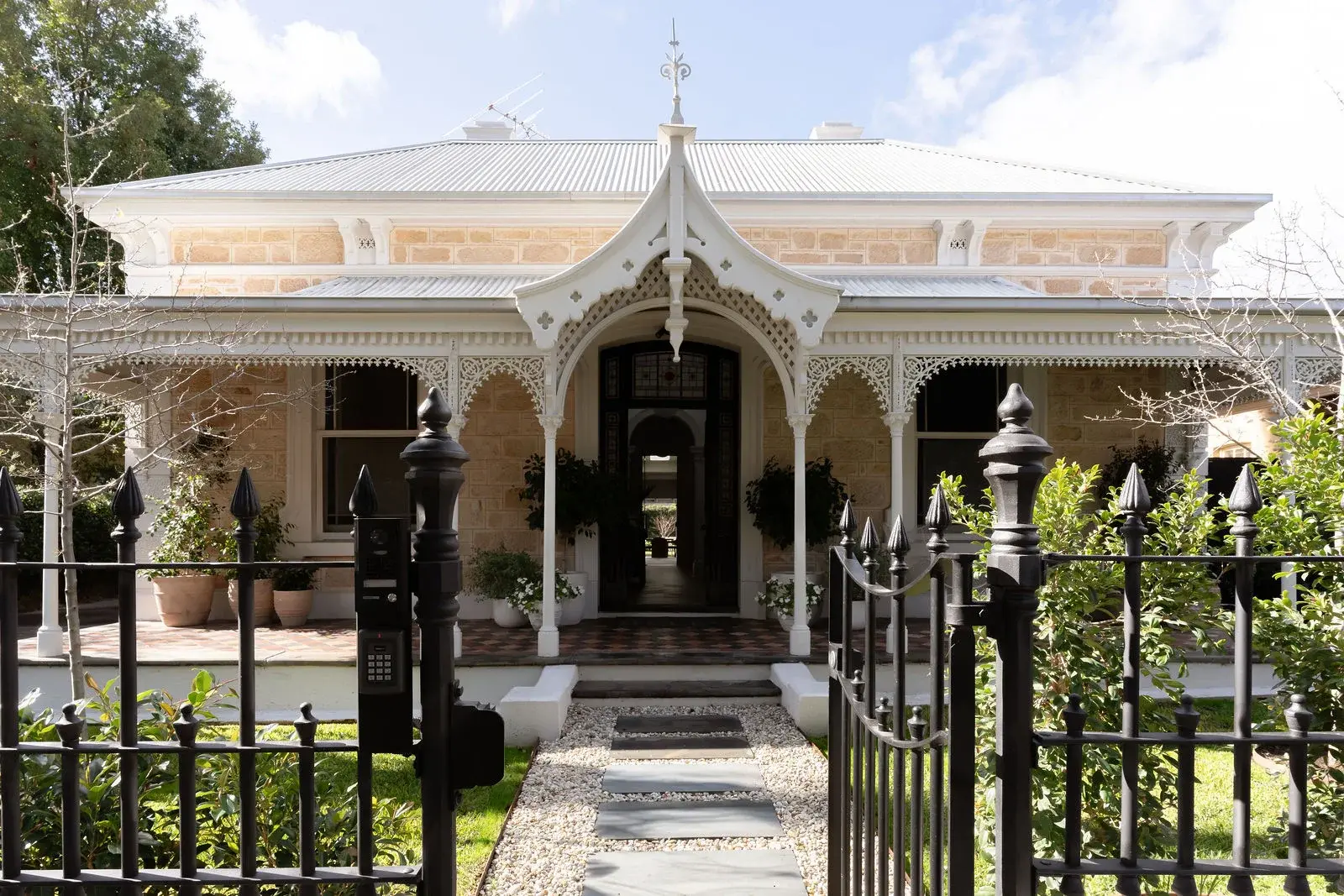 Sandstone villa facade with lacework verandah and wrought-iron gate